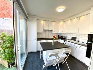 a kitchen with white cabinets and a table and chairs at Apartments Bex. in Antwerp