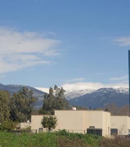 a building on a hill with snowy mountains in the background at בית בקיבוץ in Hagoshrim