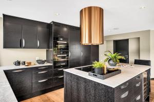 a kitchen with black cabinets and a large island at Panorama Nidelva in Trondheim