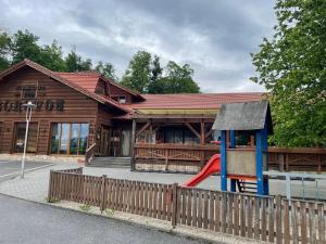 ein Holzgebäude mit einem Spielplatz davor in der Unterkunft Ubytování Pod Borovou in Malenovice