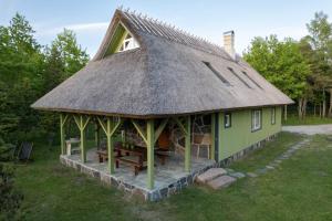 una casa con tetto di paglia e panca davanti di Kernuti House a Emmaste