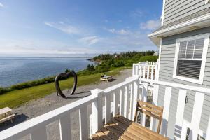 a porch with a white fence and a view of the water at North Star Beach Suites in Louisbourg