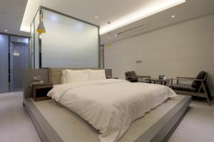 a bedroom with a large white bed with a large screen at HOTEL YUNA Business in Busan