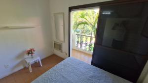 ein Schlafzimmer mit einem Bett und eine Tür mit einem Fenster in der Unterkunft Apartamento - Cond. Winbledon - Praia Toninhas in Ubatuba