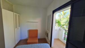 Zimmer mit einem orangenen Stuhl und einem Fenster in der Unterkunft Apartamento - Cond. Winbledon - Praia Toninhas in Ubatuba