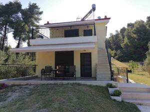 een klein geel huis met een balkon en een tafel bij EPavli Xenia Pefkochori-Paliouri 50m in Paliouri