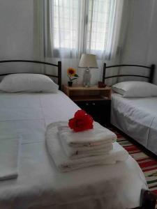 Dos camas con toallas y una rosa encima. en EPavli Xenia Pefkochori-Paliouri 50m, en Paliouri