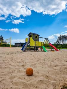 a playground with a slide and a ball in the sand at Green Valley vacation homes in Žocenes Ciems