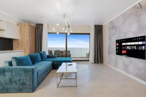 a living room with a blue couch and a view of the ocean at Gioia Sea View in Mamaia Nord