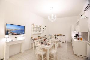 una cucina bianca con tavoli bianchi e sedie bianche di Chiaia Bridge B&B a Napoli