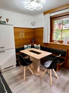 cocina con mesa, 2 sillas y nevera en Maple Appartement, en Mayrhofen