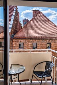 a balcony with two chairs and a view of a building at Grelewicz Apartments-MyView in Toruń