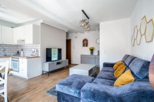 a living room with a blue couch and a kitchen at Grelewicz Apartments-MyView in Toruń