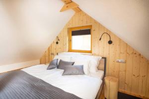 um quarto com uma cama branca num sótão em A Nest Under the Karawanks em Žirovnica