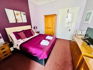 um quarto com uma cama grande e um cobertor roxo em Perfect for large groups! em Torquay