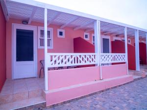 ein rosafarbenes Haus mit einer weißen Tür und einer Veranda in der Unterkunft Ta Kymata Karpathos in Karpathos