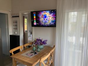 a dining room table with a tv on the wall at Philia Apartment in Artemida