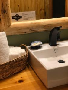 - Baño con lavabo y cesta de toallas en Summit Lake Lodge en Summit Lake