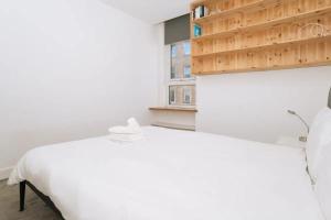 um quarto com uma cama branca e uma janela em Sleek & Central 2BD Flat - Haymarket em Edimburgo