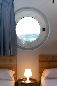 Habitación con 2 camas y ventana redonda. en LPH - Dannunziano Country House, en Chieti