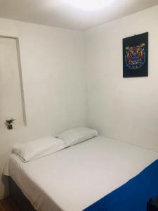 Una cama blanca en una habitación con un cuadro en la pared en hostal la 18, en Pereira