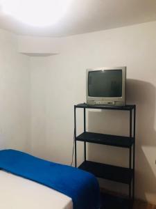a room with a bed and a television on a shelf at hostal la 18 in Pereira