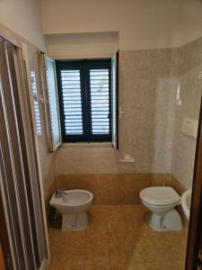 bagno con lavandino, servizi igienici e finestra di Casa vacanze Leonardo a Peschici