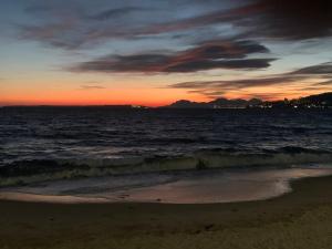 einen Sonnenuntergang am Strand mit dem Meer in der Unterkunft Grand Studio proche mer avec piscine. in Antibes