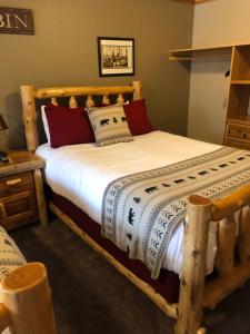 a bedroom with a wooden bed with white sheets at Summit Lake Lodge in Summit Lake