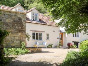 a white house with a stone wall at Spring Cottage in Stroud
