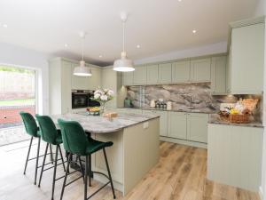 a kitchen with a large island with green bar stools at The Barn in Poole