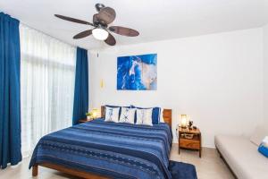 a bedroom with a blue bed and a ceiling fan at Vista al Mar - Monterosa in Sayulita