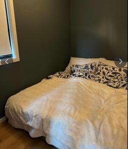 a bed in a bedroom with a white comforter at Sjønær leilighet på fevik! in Fevik