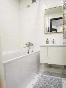 a white bathroom with a tub and a mirror at Esplanada aparments in Sumy