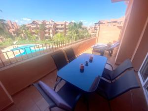 a blue table and chairs on a balcony with a pool at ENJOY Mar Menor in Torre-Pacheco