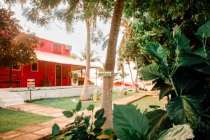 una casa roja con un cartel en una palmera en Lua Morena, en Aracati