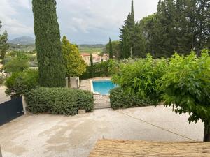 una piscina en un jardín con árboles y arbustos en Gite "Au bout du chemin", en Beaumes-de-Venise