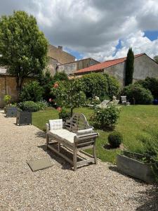 eine Holzbank, die mitten im Hof sitzt in der Unterkunft Le Jardin des Anges in Saint-Jean-dʼAngély