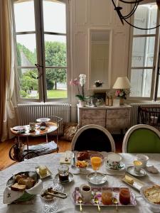 a dining room with a table with food on it at Le Jardin des Anges in Saint-Jean-dʼAngély