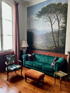 a living room with a green couch and a painting at Le Jardin des Anges in Saint-Jean-dʼAngély