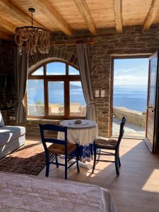 Zimmer mit einem Tisch, Stühlen und einem Fenster in der Unterkunft ΠΕΤΡΙΝΟ στην Άνδρο in Agia Eleousa