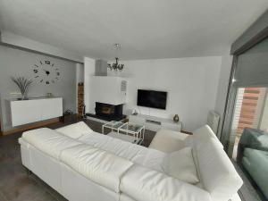 a white couch in a living room with a clock on the wall at Adosado en Cirueña con Chimenea y barbacoa in Cirueña