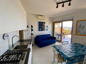 a kitchen with a sink and a blue couch at A Punta Tegge il mare la spiaggia il tramonto in La Maddalena