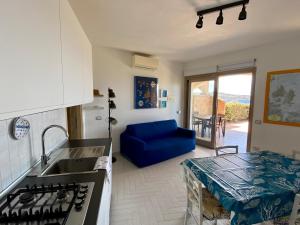 a kitchen with a sink and a blue couch at A Punta Tegge il mare la spiaggia il tramonto in La Maddalena +26 photos