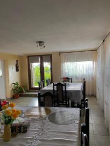 a dining room with two tables and chairs with flowers on it at Pensiunea Angelica in Baia de Fier