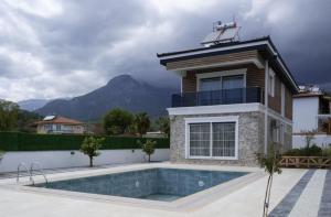 a villa with a swimming pool in front of a house at Amore Hotel Teki̇rova in Tekirova