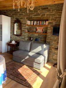 a living room with a couch and a brick wall at ΠΕΤΡΙΝΟ στην Άνδρο in Agia Eleousa