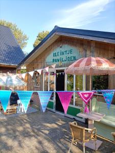 un bâtiment avec une table et des parasols devant lui dans l'établissement Minicamping Kleintje Zandpol, 