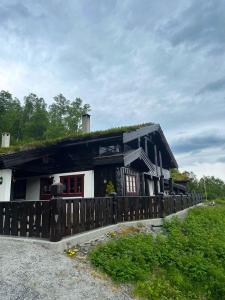 a house with a grass roof with a fence at Roalden Mountain Lodge in Stranda