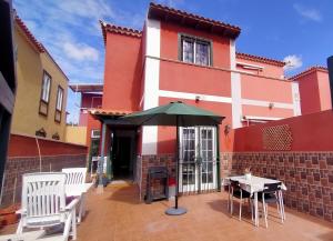 un patio con sombrilla frente a una casa en La casita en Arona